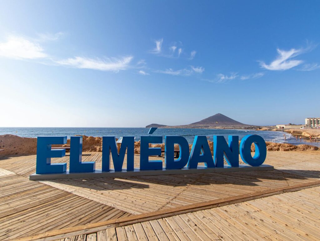 Beautiful view of El Médano sign on the seashore in Spain, with ocean and volcanic landscape.