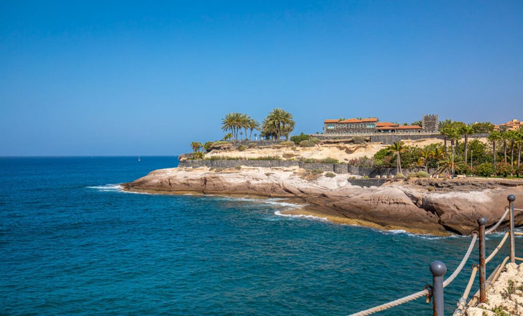 Beautiful coastal scenery at Costa Adeje, with clear blue waters and rocky cliffs under a sunny sky.