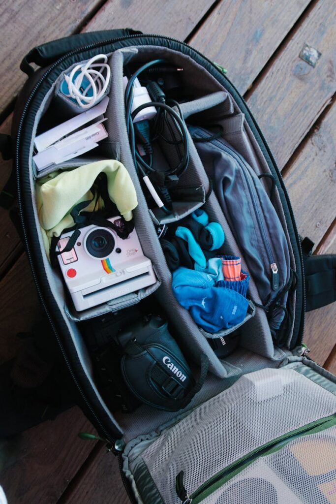 Close-up of an open backpack filled with photography equipment on a wooden floor.