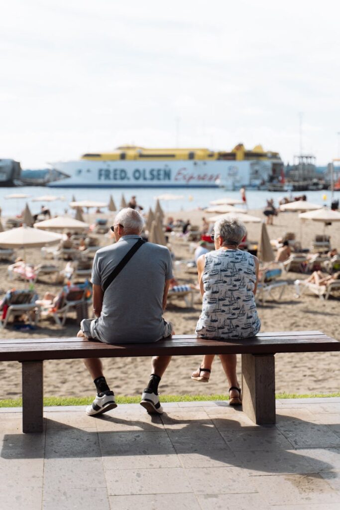 Elderly couple enjoying a serene beach day with Fred. Olsen ferry in the background.