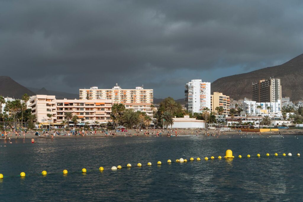 Beachfront scene with hotels and a vibrant coastline under moody skies in Canary Islands.