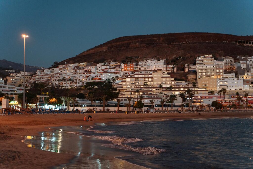 Evening view of Los Cristianos with illuminated buildings along the beach, a perfect travel destination.