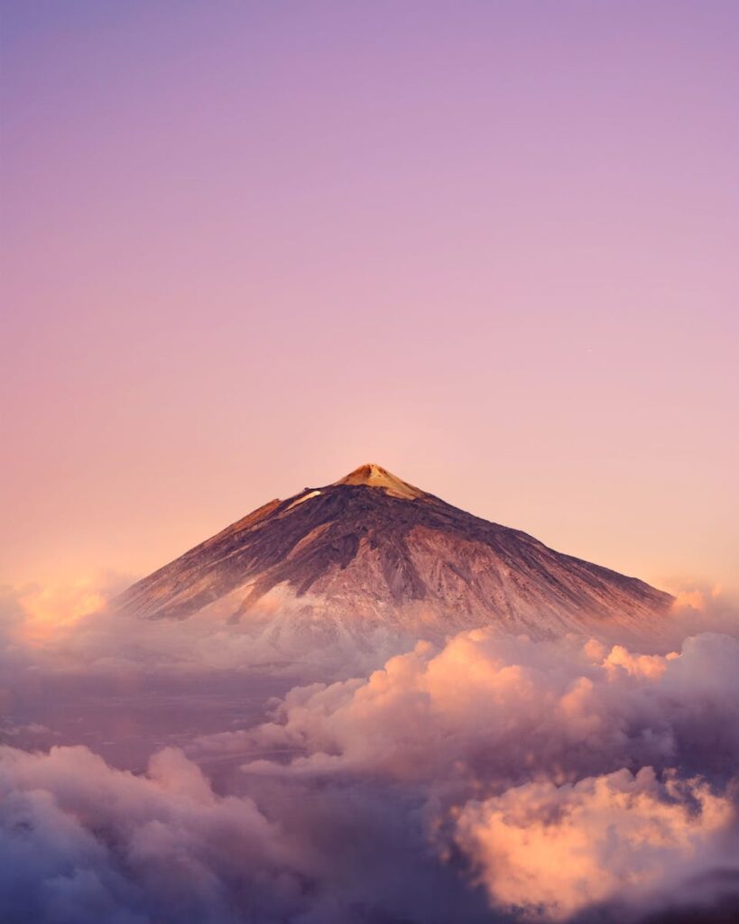 Stunning view of Mount Teide at sunrise surrounded by vibrant clouds and serene sky.