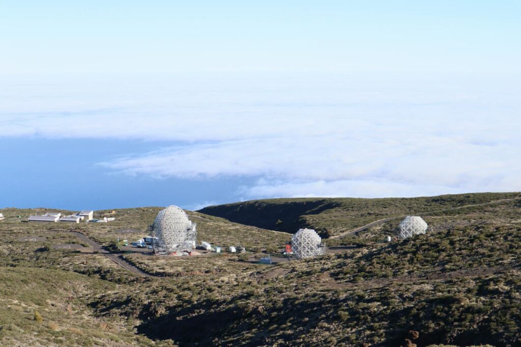 Aerial view of observatories on a rocky landscape by the sea, under open sky.