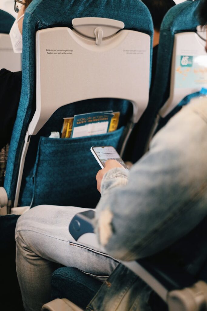 Passenger using smartphone while seated on airplane for entertainment or work.