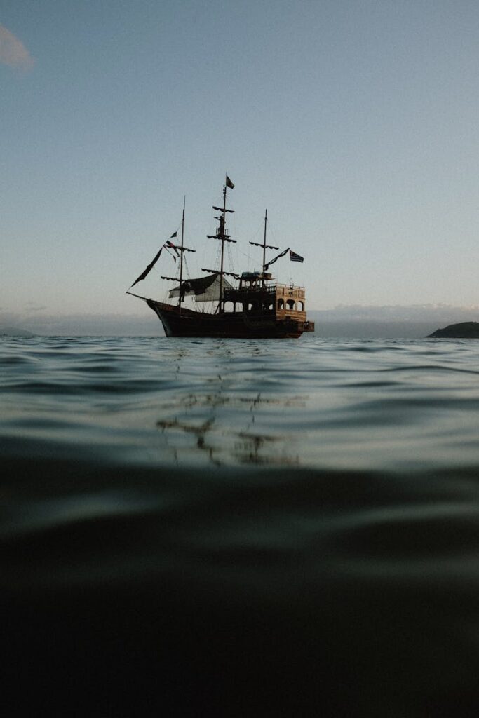 A serene pirate ship sailing on calm waters during sunset in Ubatuba, Brazil.
