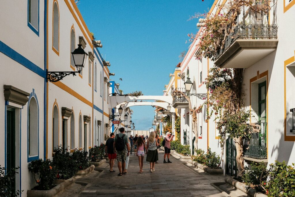 A group of people walking down a street next to tall buildings
