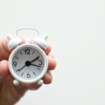 person holding white mini bell alarmclock