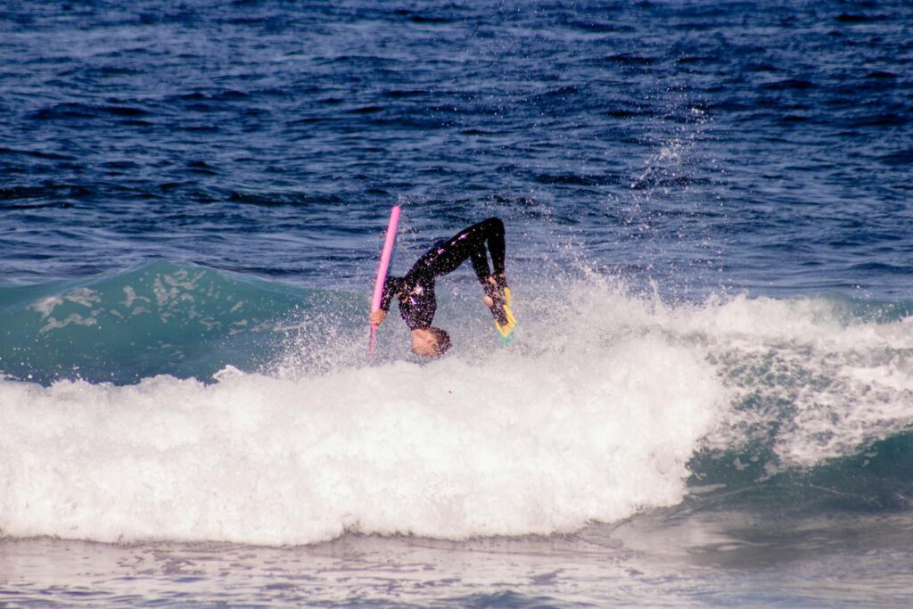 A surfer skillfully rides a wave at a stunning beach in Tenerife, Spain.