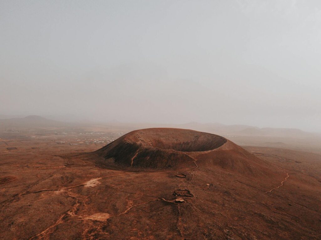 Stunning aerial view of Calderon Hondo volcano amidst a foggy, arid landscape in Spain.