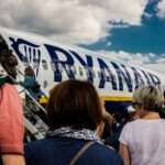 people sitting on chair near blue and white airplane under white clouds during daytime