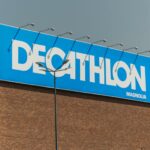 Close-up of a Decathlon store sign against a clear sky on a brick building.