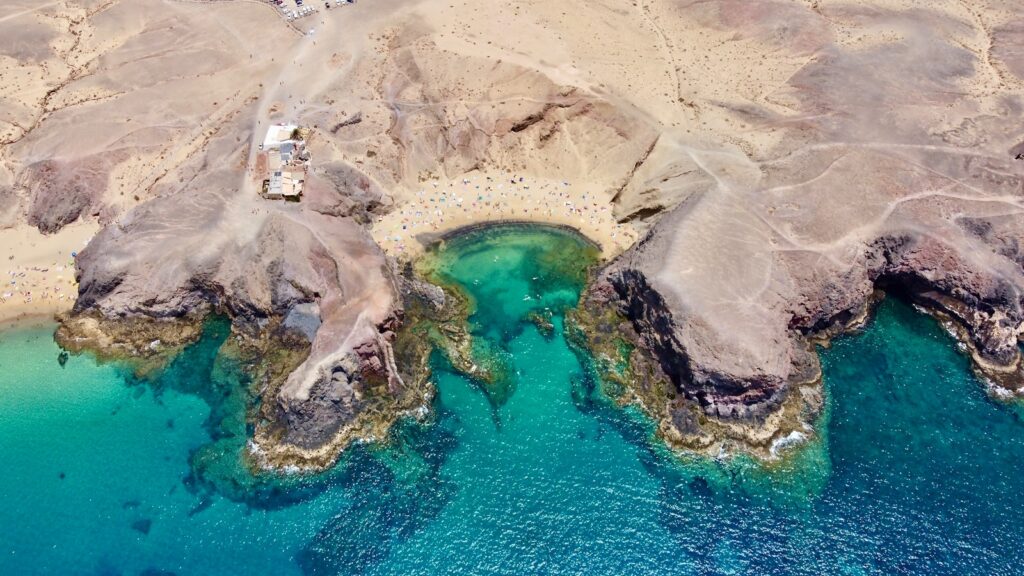 an aerial view of a sandy beach with clear blue water
