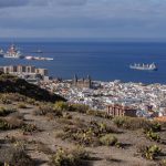 A panoramic view of Las Palmas de Gran Canaria with the ocean and harbor in view, captured from a hilltop.